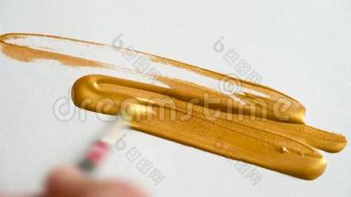 用画笔在白纸上画，用明亮的金色丙烯酸<strong>颜料画</strong>得很近